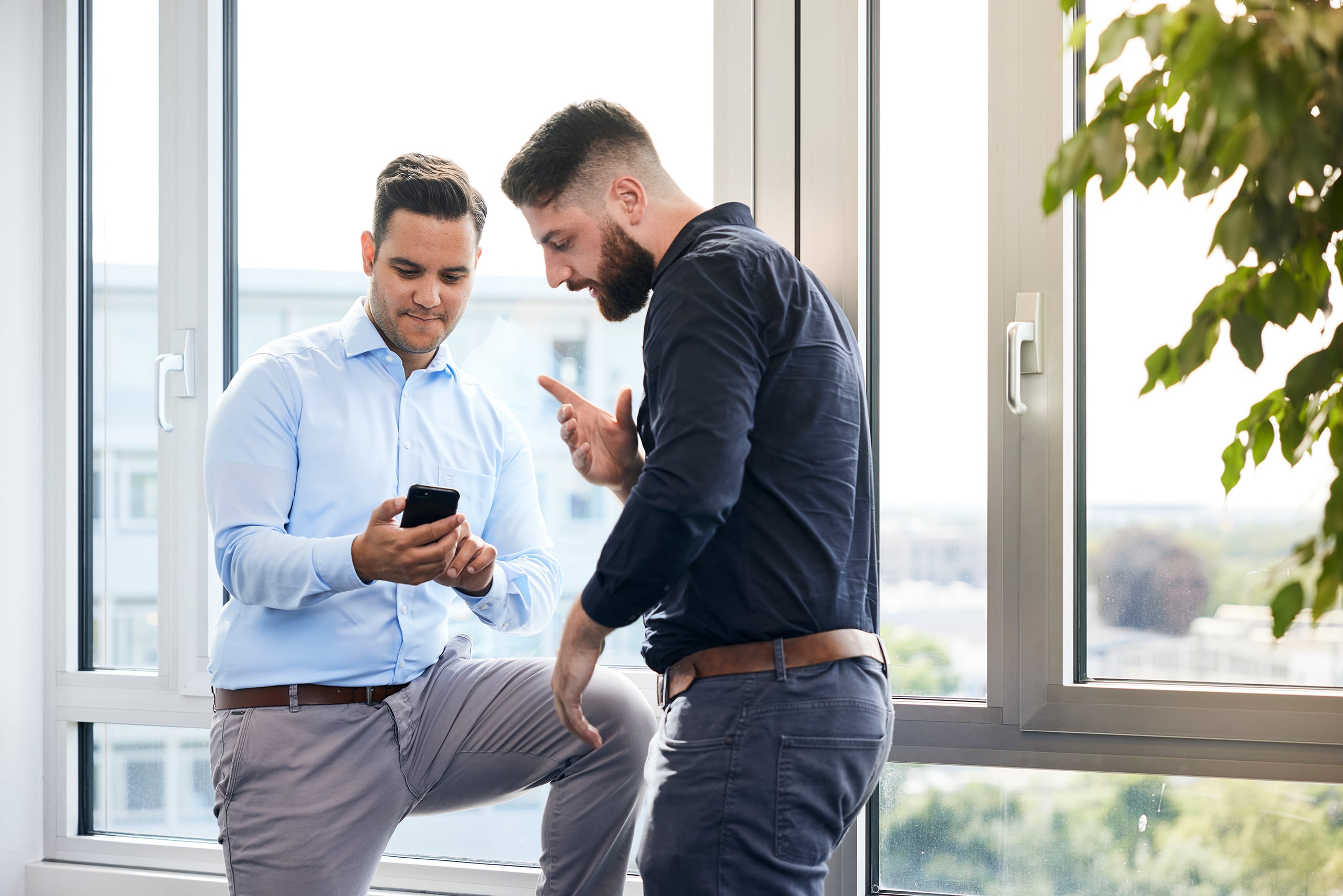 Zwei Männer beratschlagen am Mobiltelefon