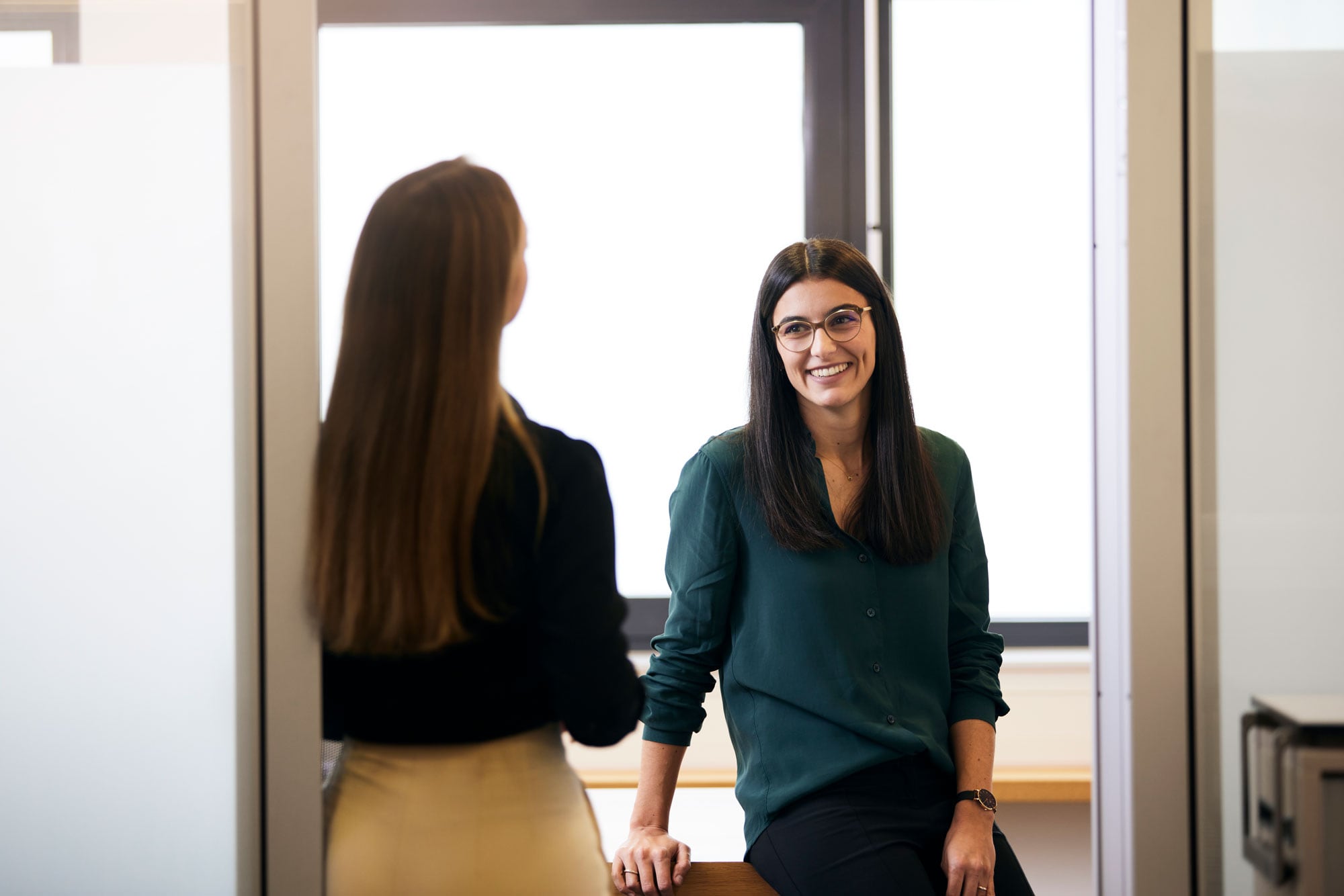 Zwei Kolleginnen unterhalten sich auf dem Büroflur