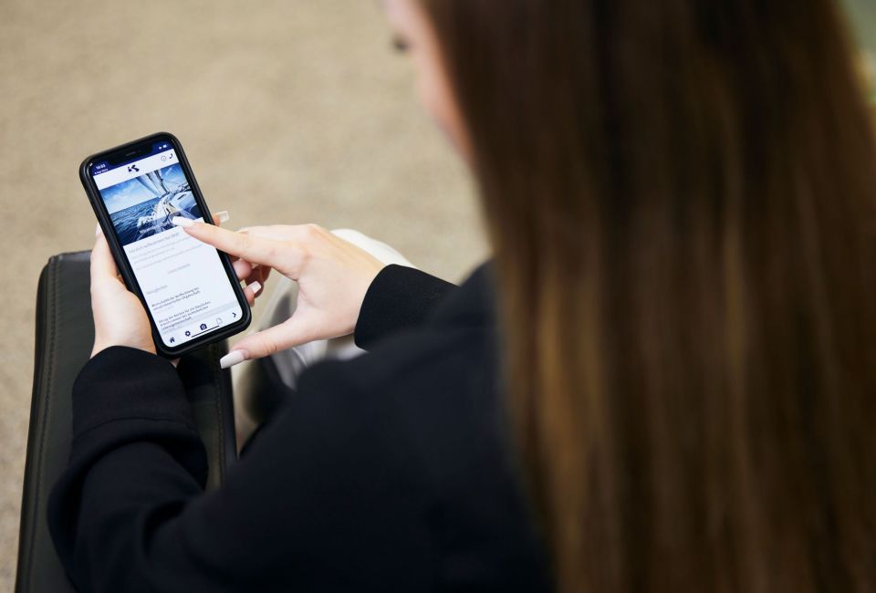 Frau schaut auf Mobiltelefon mit geöffneter Mandanten-App